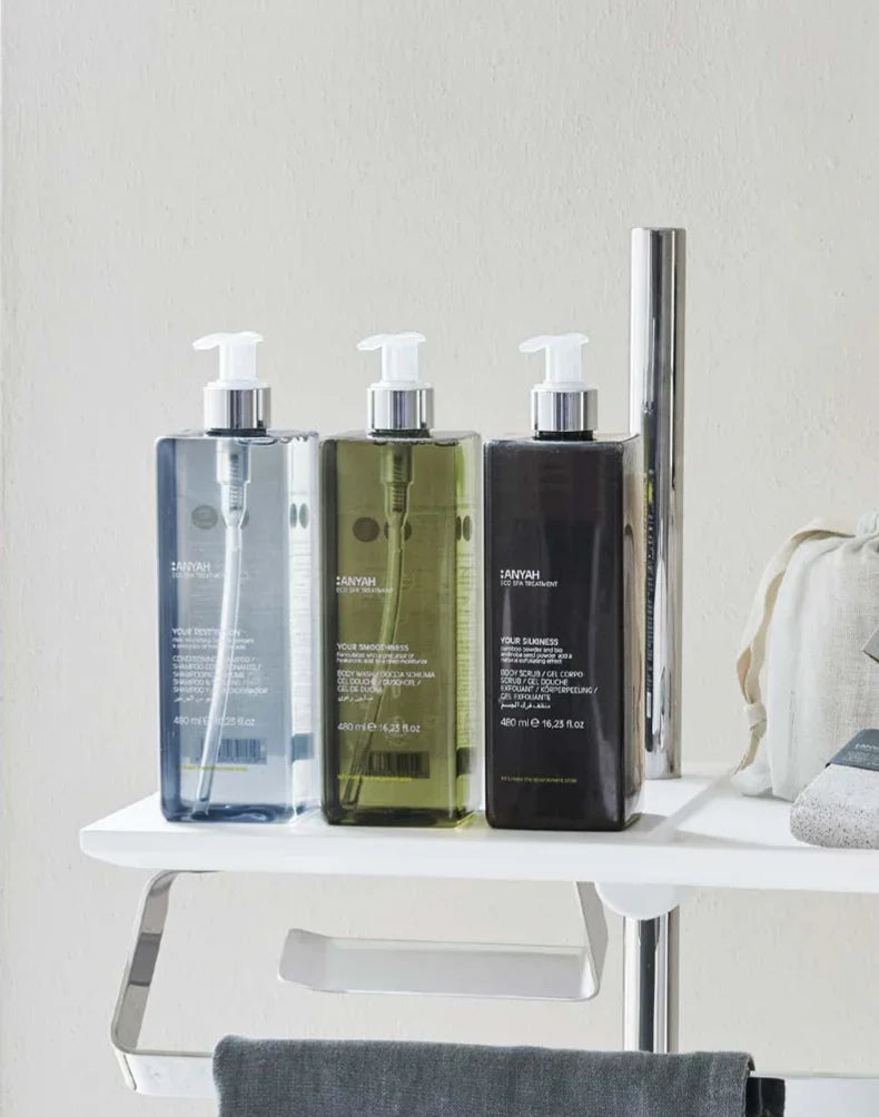 Loção Hidratante Corporal Ecológica ANYAH em embalagem de 400ml disponível em três cores sobre uma prateleira de banheiro, formato amenities, perfeito para hotéis e alojamentos locais