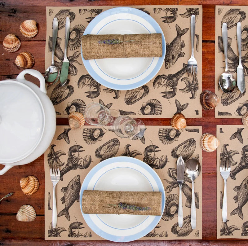 Toalhas de Mesa Offset Kraft Impressas Decoradas em mesa com pratos e talheres, padrão náutico e estilo rústico.