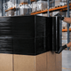 Filme Estirável Preto Manual para Paletização sendo aplicado em caixa, ideal para segurança e proteção em uso num armazém industrial de logística