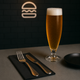 Guardanapos de Mesa Pretos Dobrados 1-6 PPP 30x40cm com talheres e copo de cerveja em ambiente de restaurante.