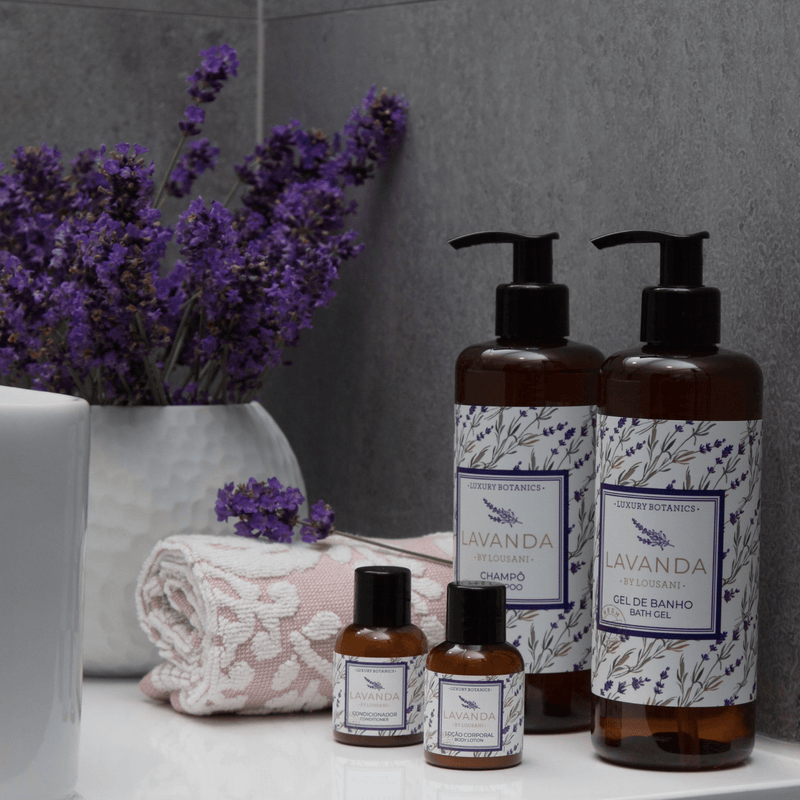 Conjunto de produtos de higiene incluindo Gel de Banho Lavanda da LOUSANI, champô e loções, decorados com flores de lavanda, para uso em hotéis e alojamentos locais