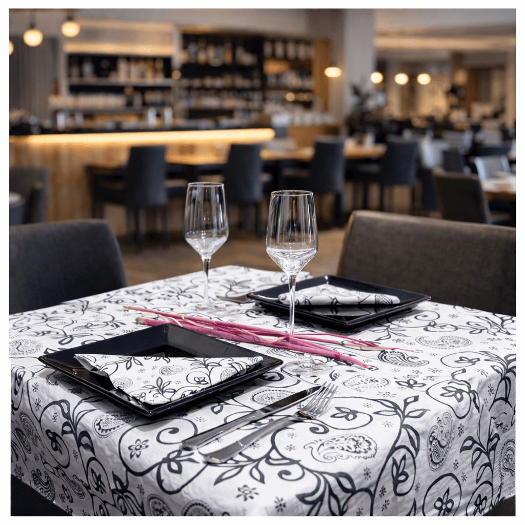 Toalhas de Mesa Decoradas em Bloco em ambiente de restaurante, mesa com pratos e copos elegantes.
