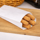 Papel Bolsa Anti-Gordura Branca 14x24 cm com churros frescos embalados, ideal para food service.